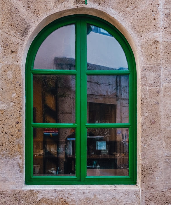 Moosgrünes Fenster in heller Steinfassade