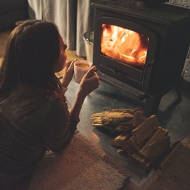 Frau mit Tasse Tee vor wärmendem Kamin